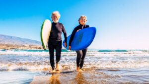 Mature couple walking on shore with surf boards