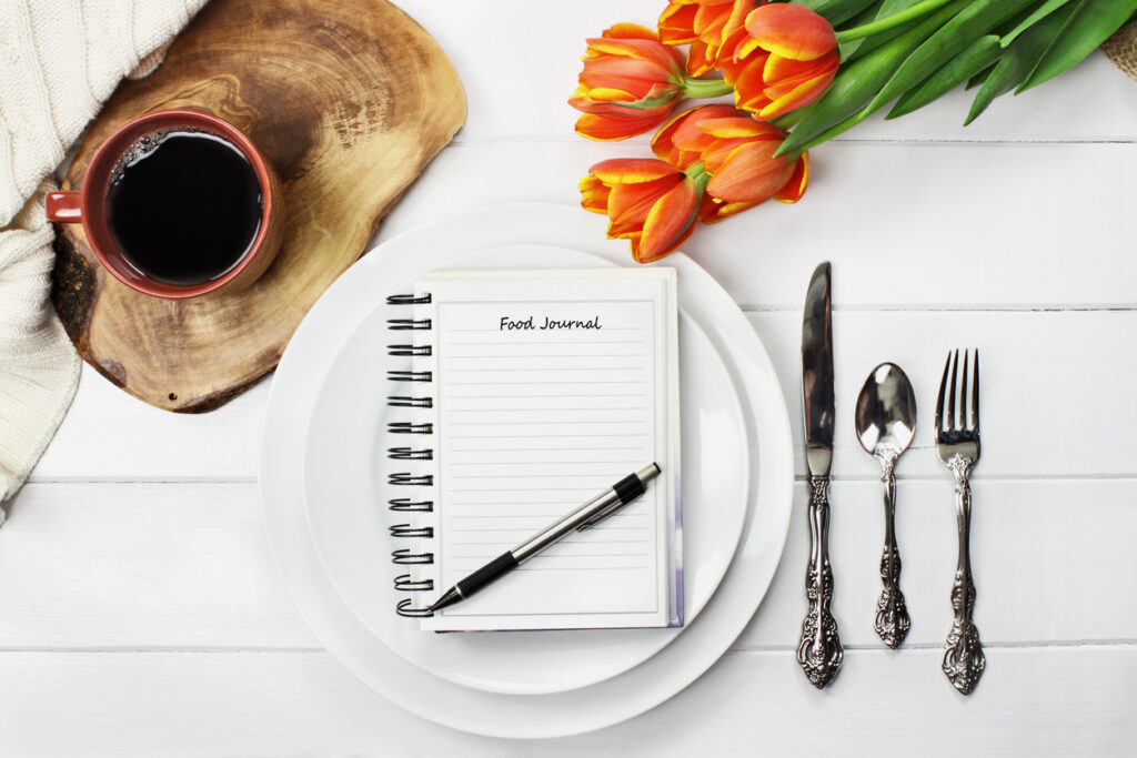 A notebook on a plate with a pen and silverware next to a cup of coffee, Understanding Your Diet: The Power of Record Analysis