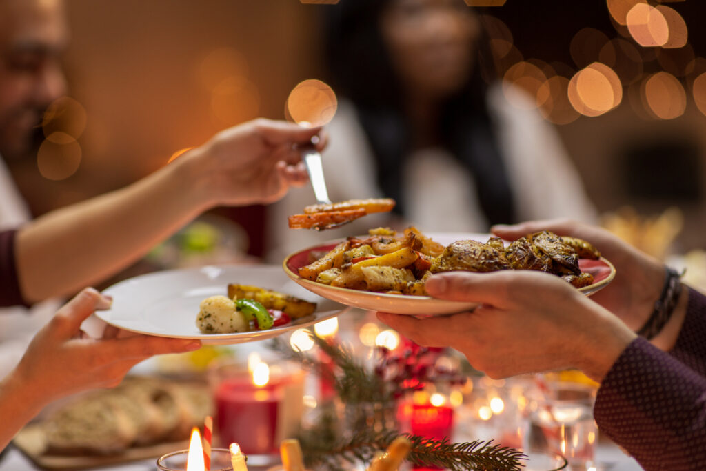 holidays, eating and celebration concept - close up of friends having christmas dinner at home and sharing food, Mindful Eating for the Holidays: Savor, Celebrate, Stay Healthy