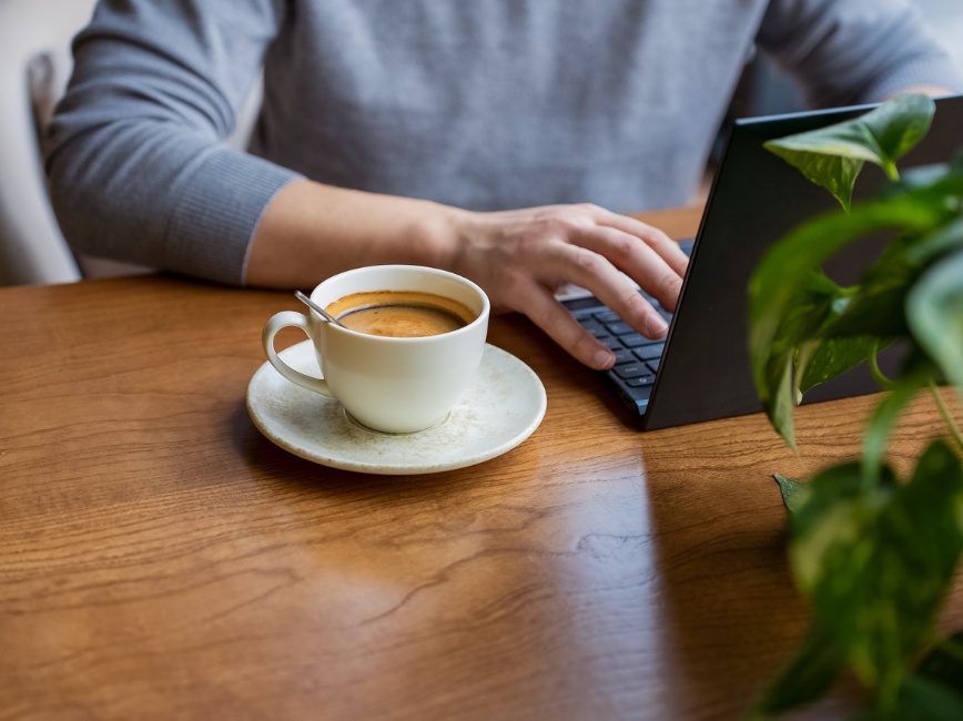  Hydration boosts longevity, A picture of a person working on their laptop with a cup of coffee next to them