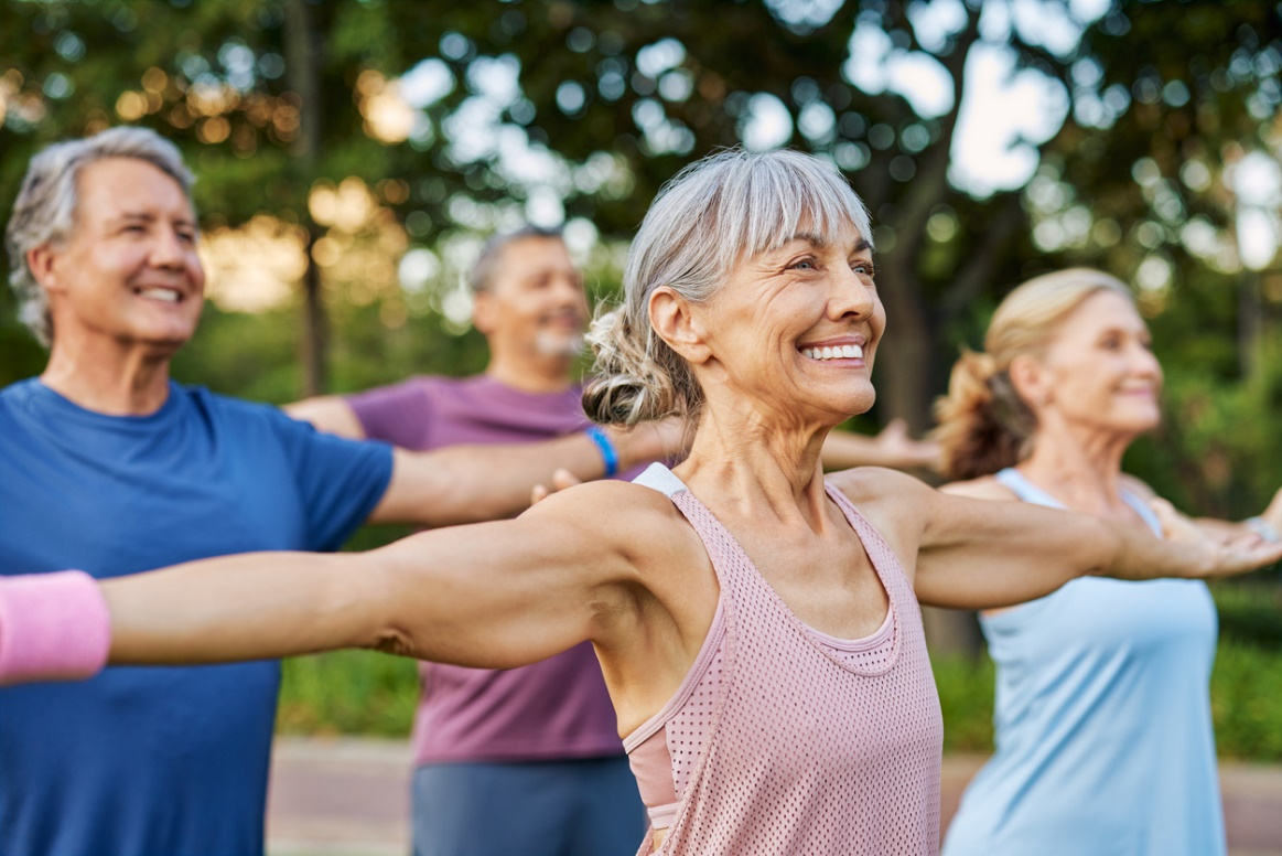 Four happy seniors stretching arms out in an outdoor exercise class., longevity-focused heart health