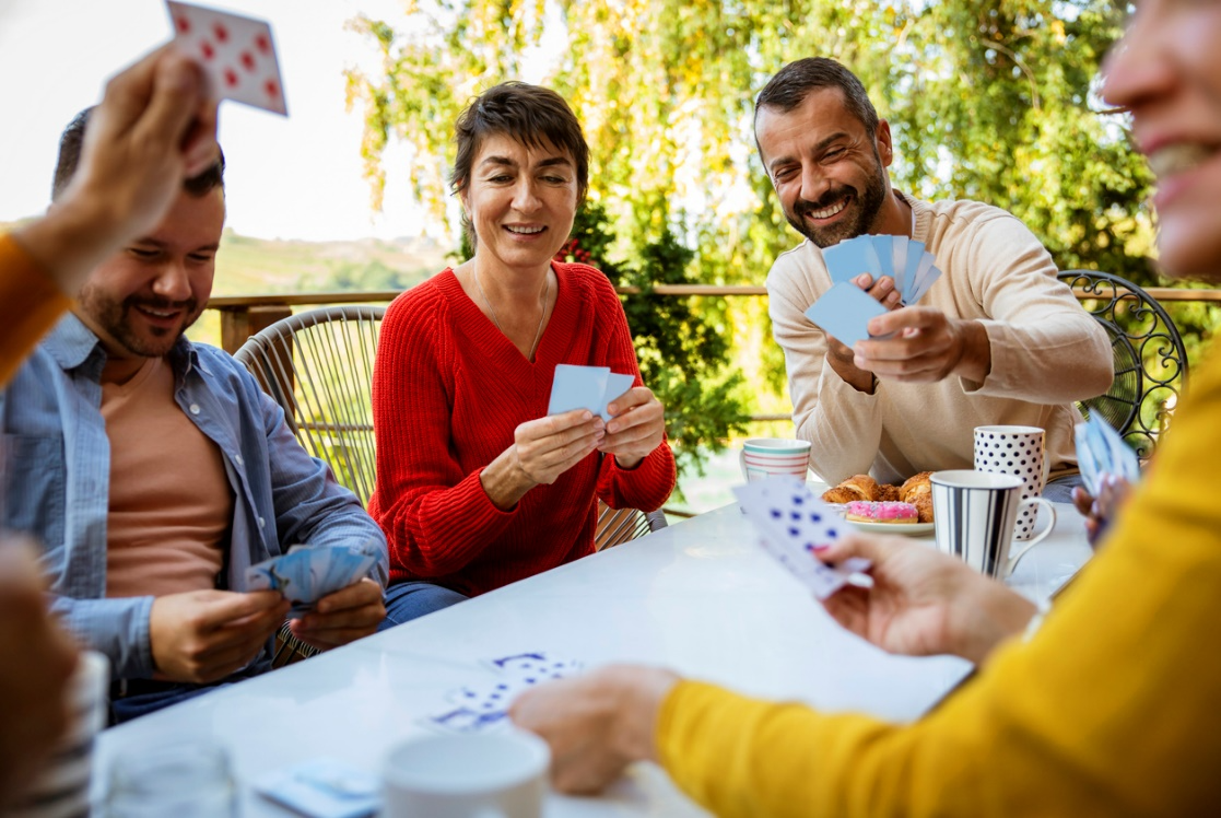 Adults playing cards together outdoors, supporting social connection and mental engagement for healthy aging
